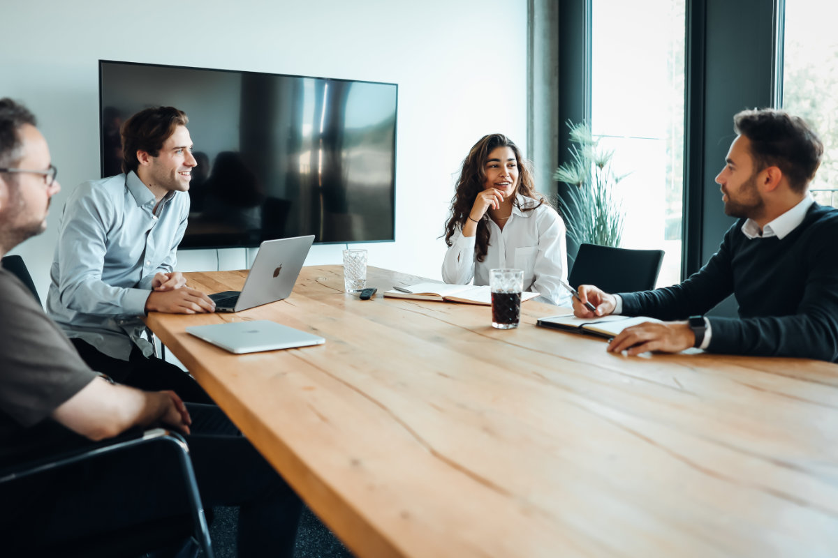 Ein Team aus Softwareentwicklern bespricht in einem Meeting neue IT-Projekte. Die offene Büroumgebung unterstützt agile Zusammenarbeit und digitale Strategieentwicklung.