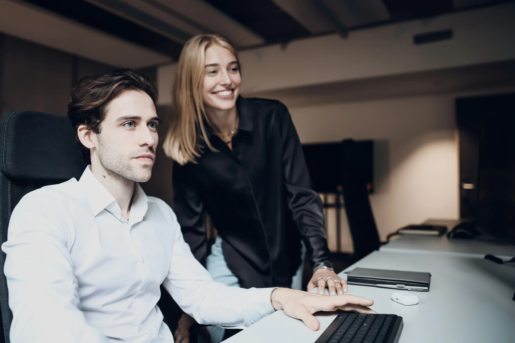 Zwei Personen arbeiten gemeinsam am Computer in einem modernen Büro