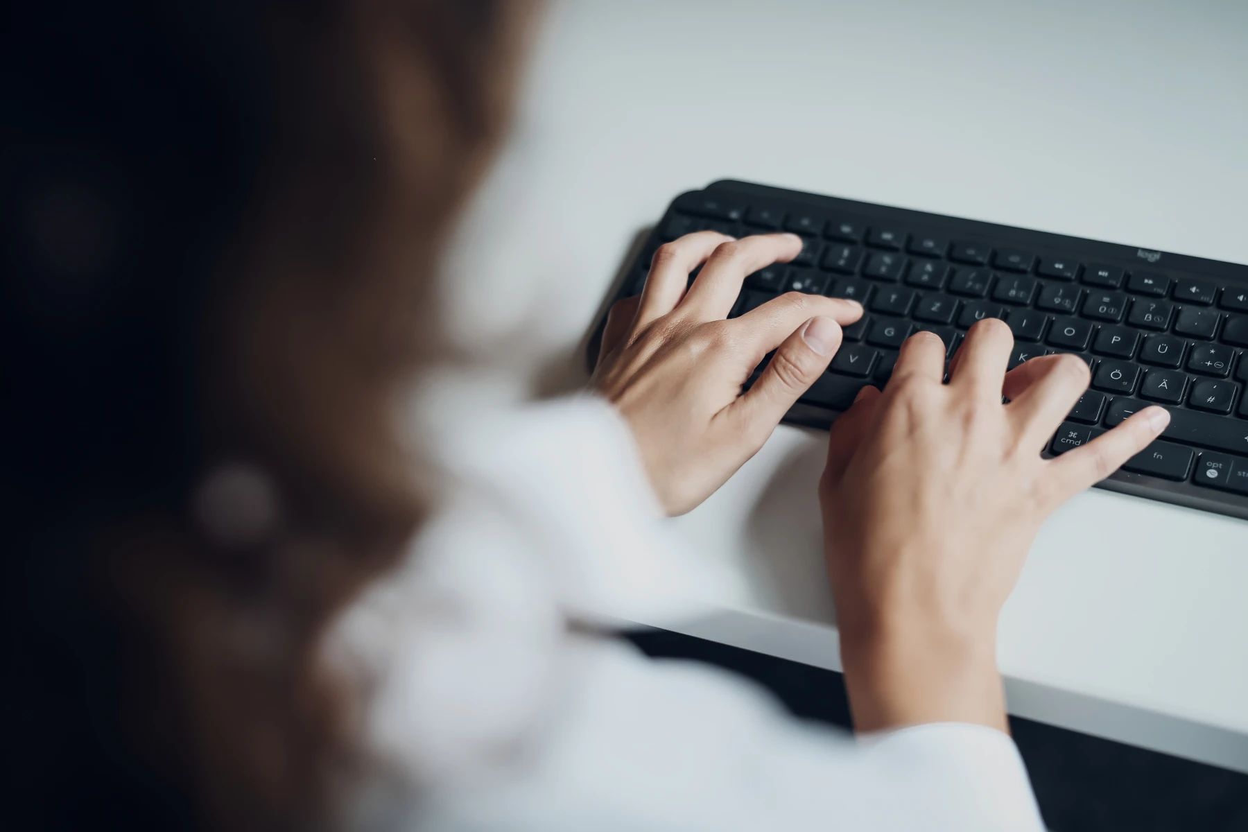 Hände einer Person beim Tippen auf einer Tastatur am Arbeitsplatz